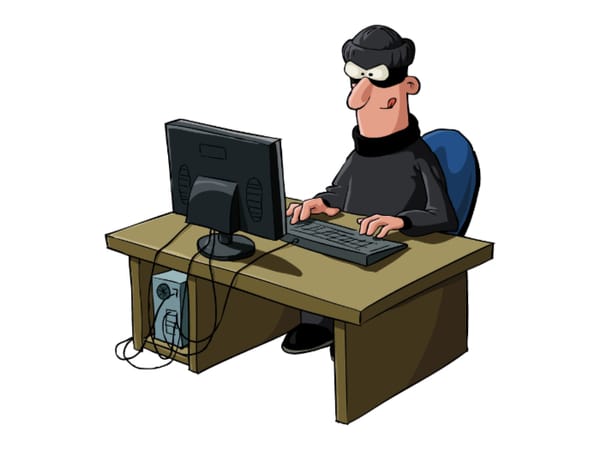 Prototypical hacker sitting at desk.